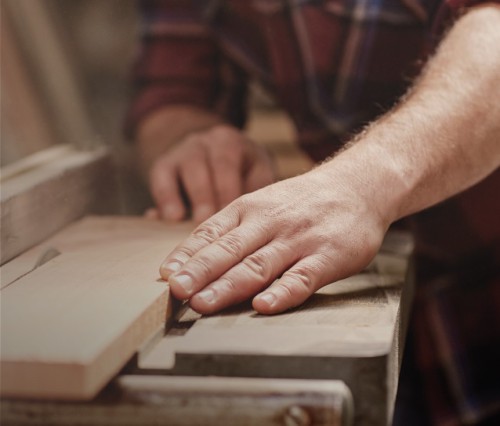 Image d'une main en train de travailler le bois.